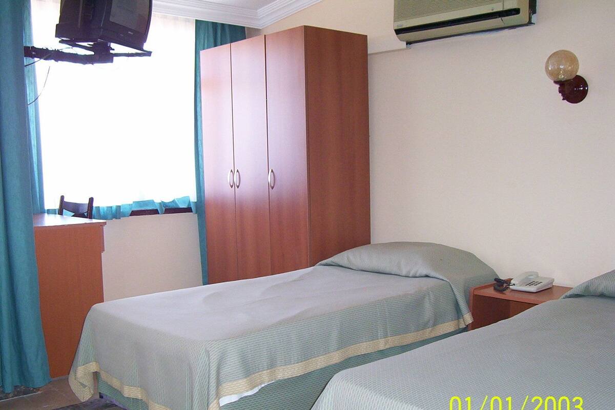 Habitación de hotel con dos camas, un escritorio, televisor y armario.