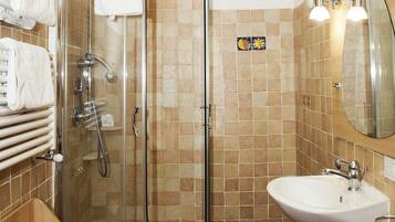 Ein modernes Badezimmer mit einer gläsernen Duschkabine, einem weißen Waschbecken und einem Holz-Waschtisch.