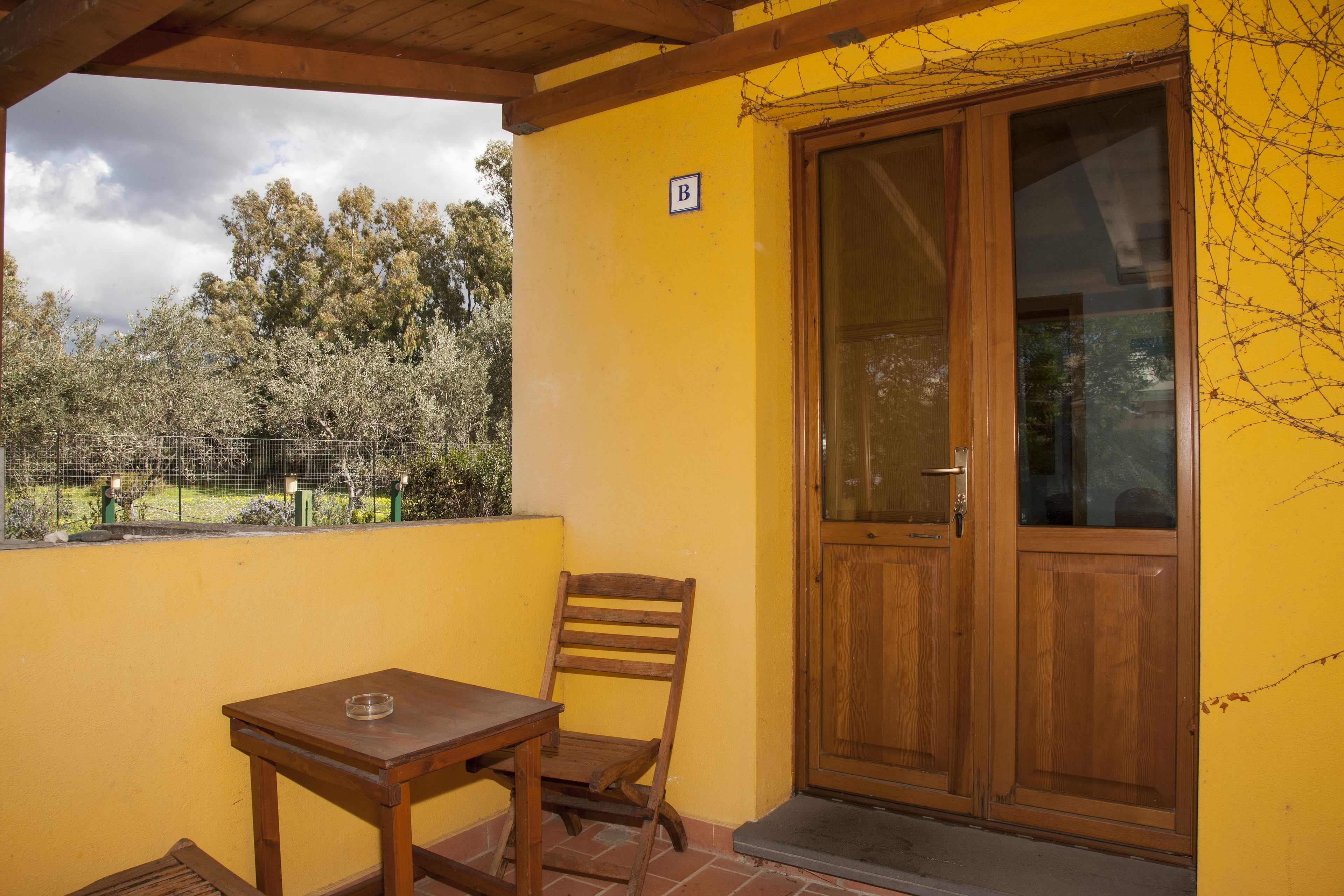 A yellow wall with a wooden door and a small table with a chair.