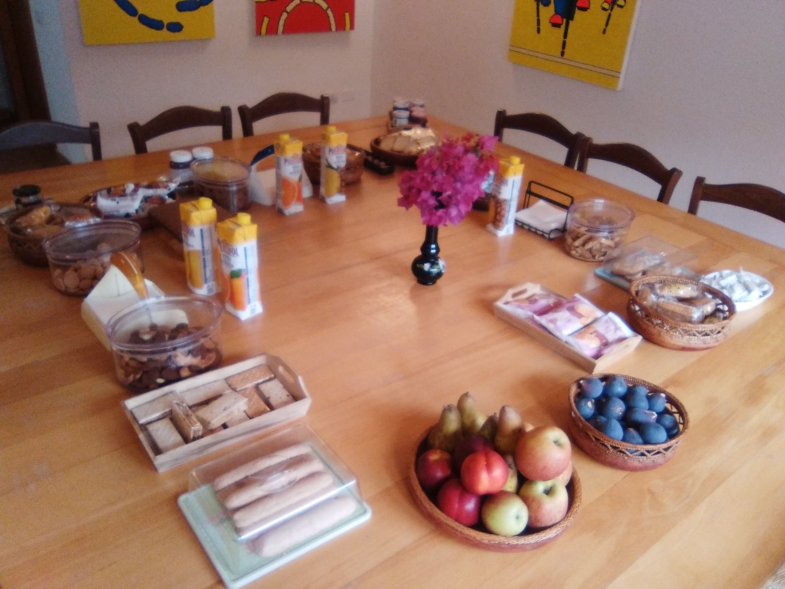 A dining table with various food items and condiments, including a vase with flowers, arranged for a meal.