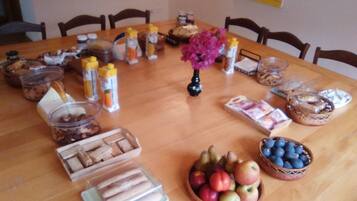 A dining table with various food items and condiments, including a vase with flowers, arranged for a meal.