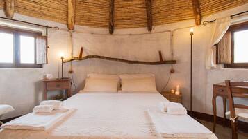 A cozy bedroom with a bed, bedside tables, a chair, and a hanging light fixture.
