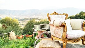 A luxurious outdoor seating area with a vintage chair and bench, surrounded by potted plants and overlooking a scenic landscape. - Essenza Sardegna (Torpe)
