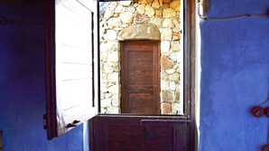 A stone wall with a wooden door and a metal gate. - Essenza Sardegna (Torpe)
