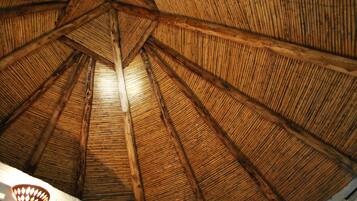 Estructura de techo de paja con vigas de madera y un accesorio de iluminación.