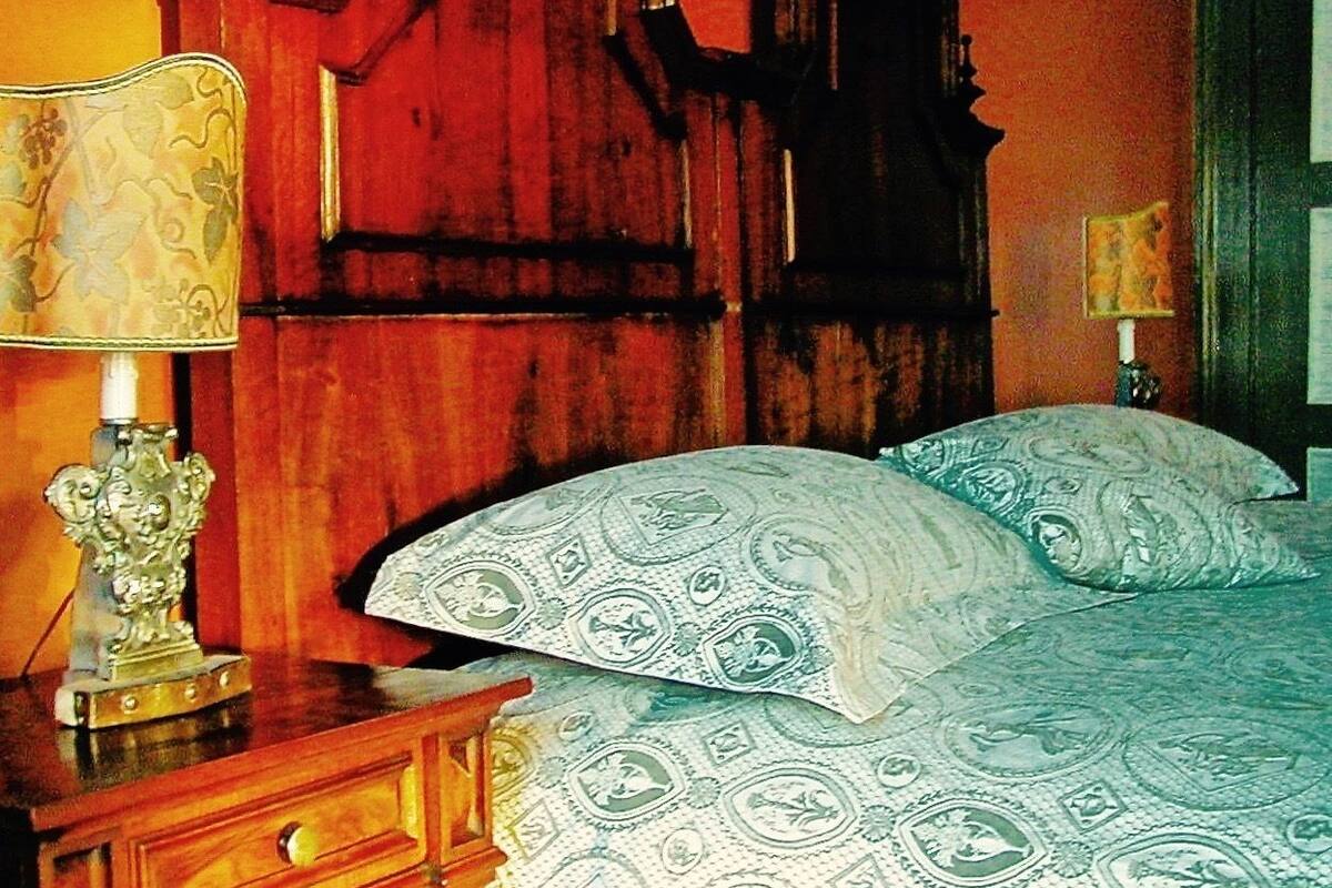 Une chambre à coucher avec une tête de lit en bois, une table de chevet avec une lampe et une literie à motifs.