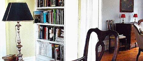 Une pièce avec une bibliothèque, une lampe et deux chaises.
