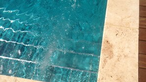 A swimming pool with clear water, surrounded by a tiled deck and wooden flooring. - Hôtel Notre Dame (Collobrieres)