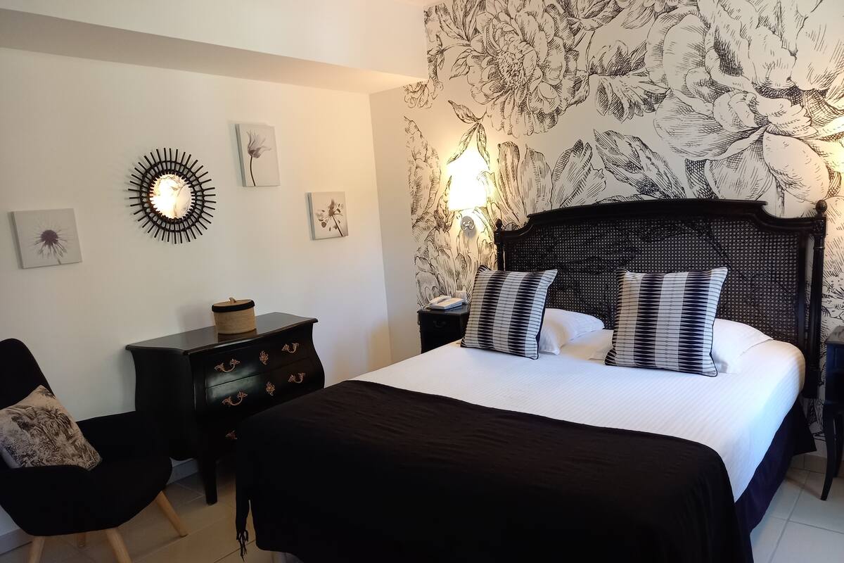A bedroom with a large bed, a nightstand, a dresser, and a chair.
