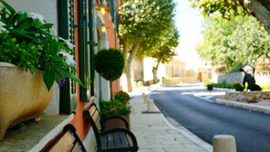 A bench on a sidewalk with a planter on the left. - Hôtel Notre Dame (Collobrieres)