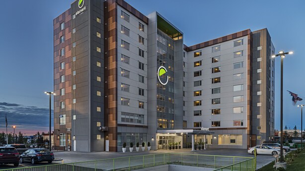 Un hotel moderno con un logotipo destacado, varios pisos y una entrada bien iluminada.