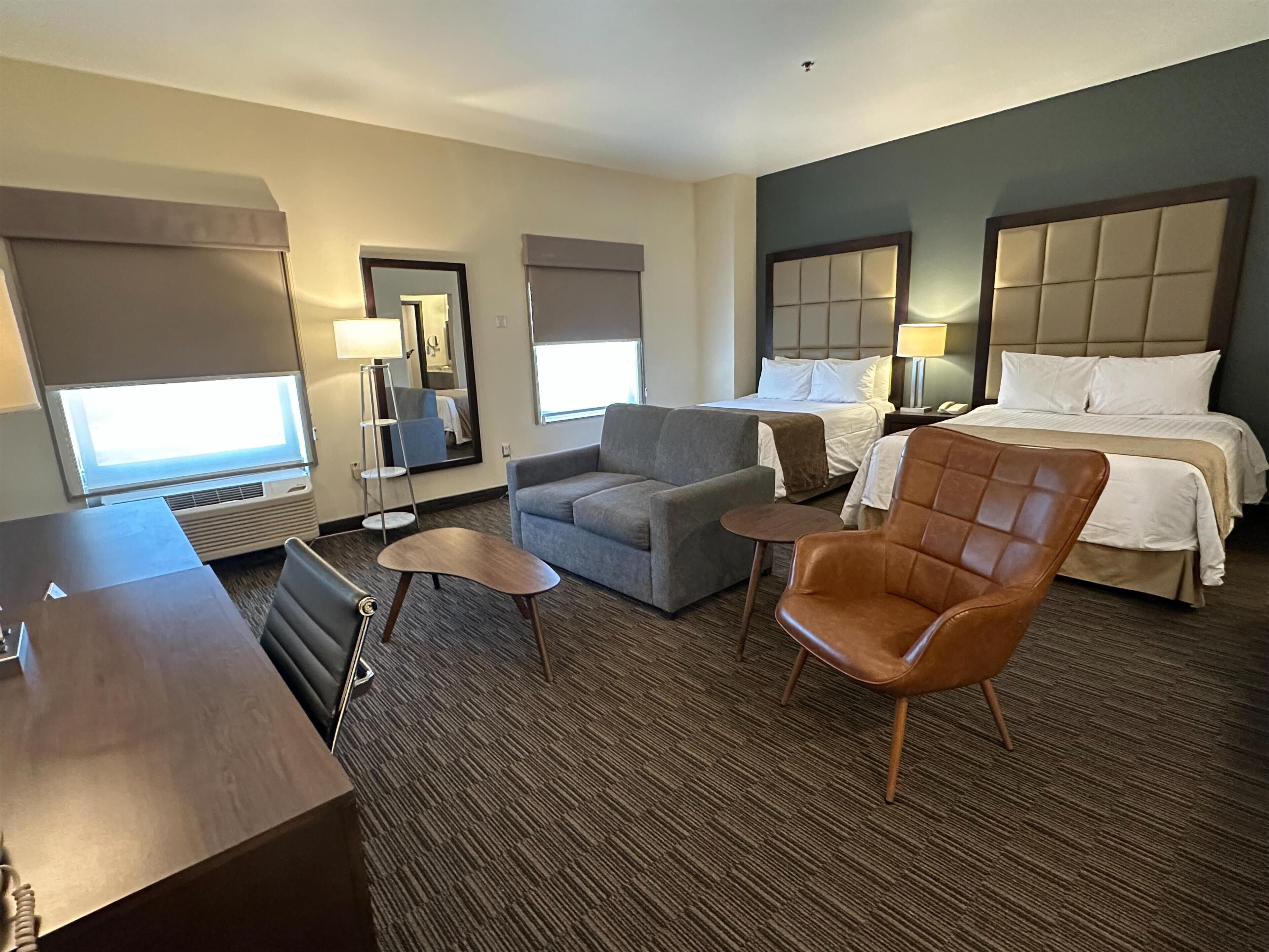 Habitación de hotel con una cama, dos sillones, un sofá, un escritorio y una mesita.