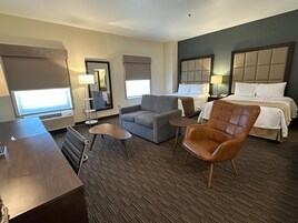Habitación de hotel con una cama, dos sillones, un sofá, un escritorio y una mesita.