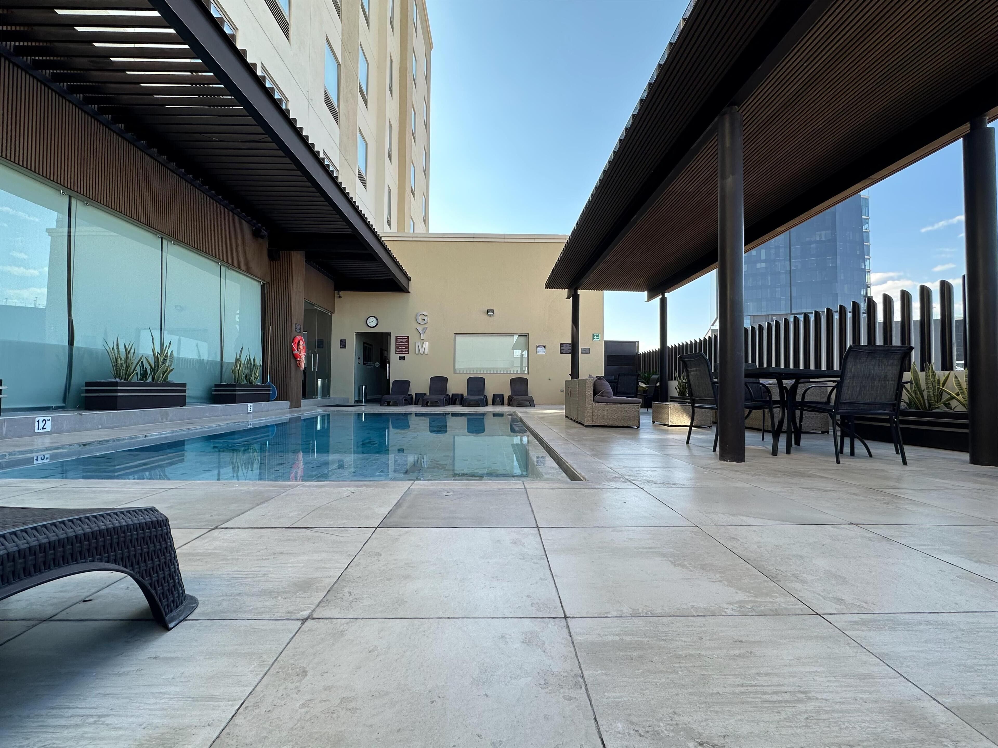 A rooftop pool area with lounge chairs and a covered seating area.