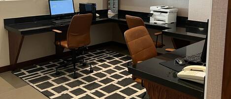 A modern office with two desks, chairs, a large mirror, shelves with decorative items, and a patterned rug.