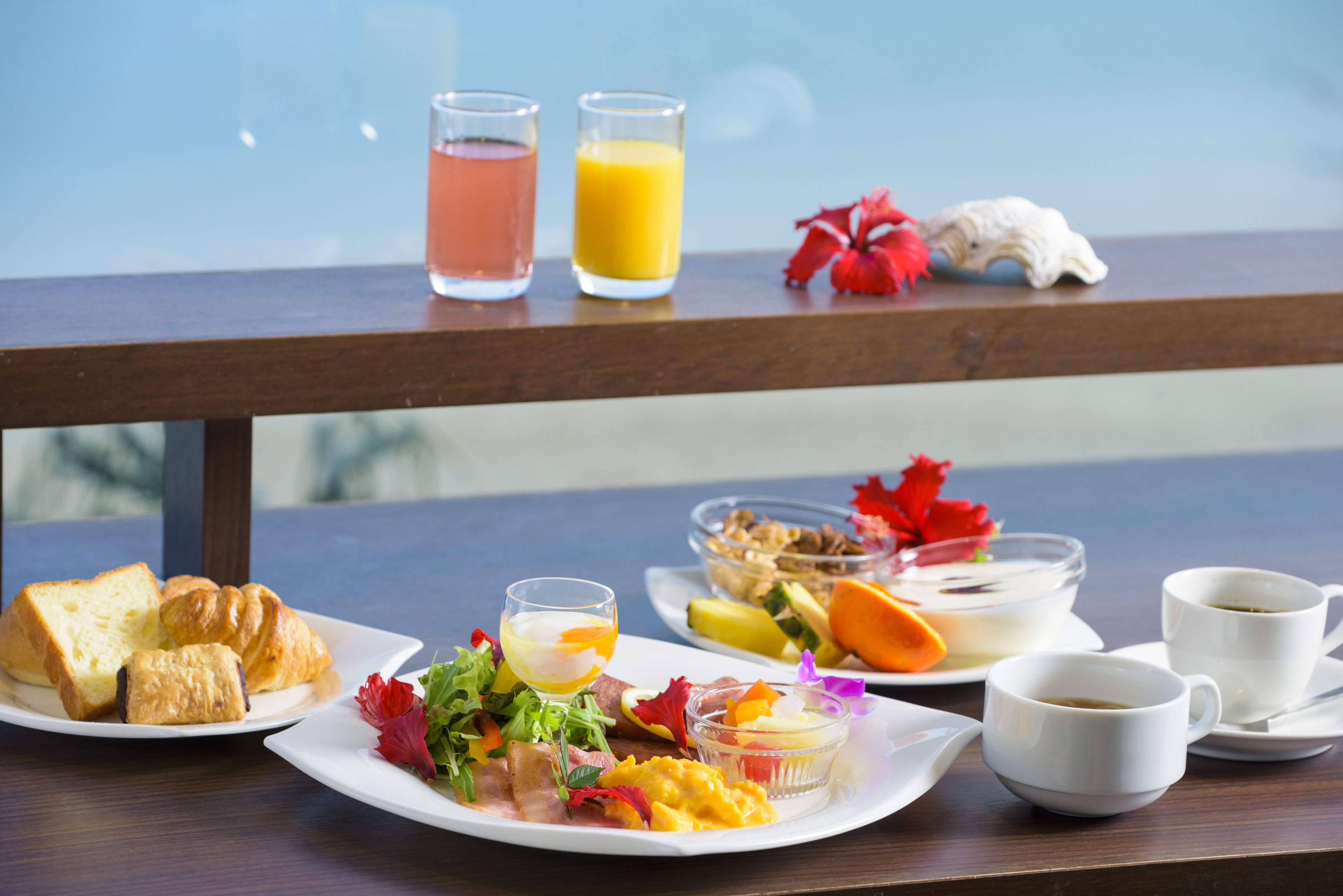 Una mesa de desayuno con croissants, ensalada de frutas, un vaso de jugo de naranja y una taza de café.