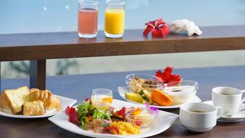 Una mesa de desayuno con croissants, ensalada de frutas, un vaso de jugo de naranja y una taza de café.