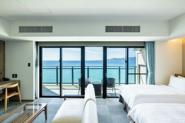 Habitación de hotel con un amplio ventanal corredero que da a un balcón con vista al mar.