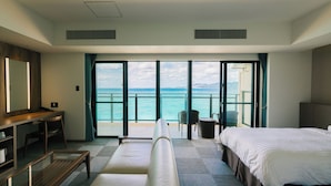 Een hotelkamer met balkon, bed, bureau en stoel.