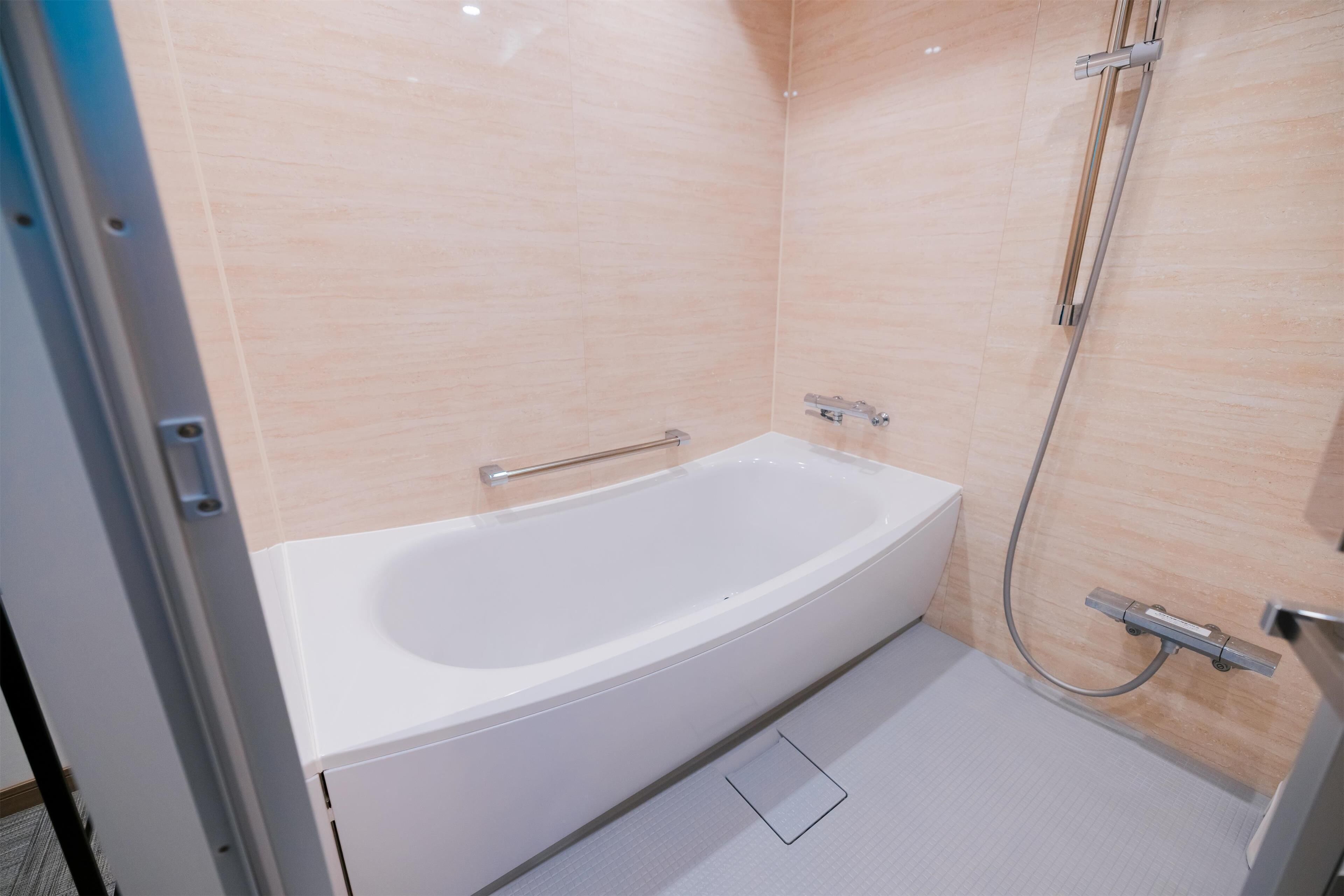 Ein modernes Badezimmer mit einer weißen Badewanne, einer Handbrause und einer Duschkabine.