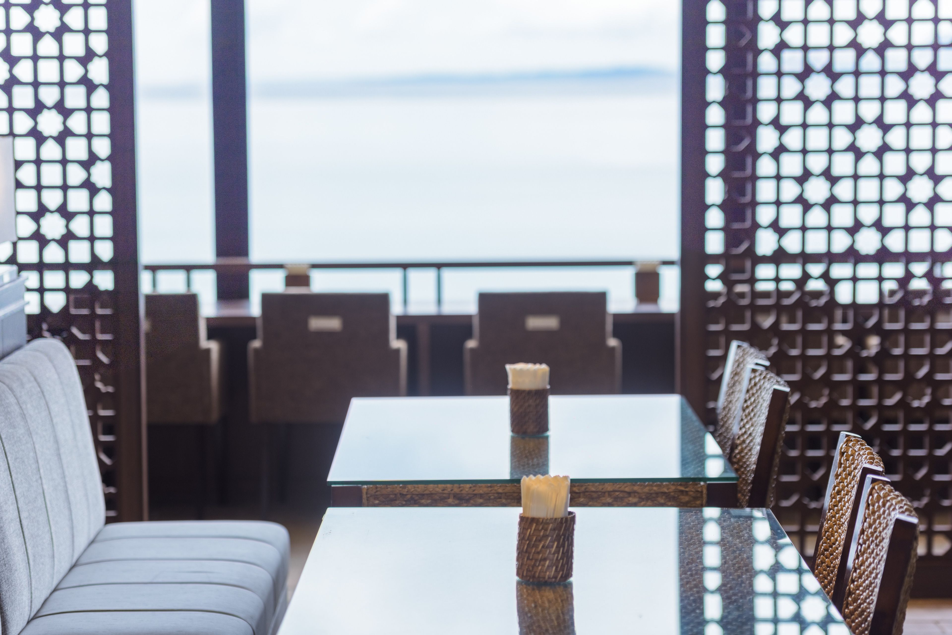 Un comedor con una mesa y sillas de vidrio, un sofá y vista al mar.