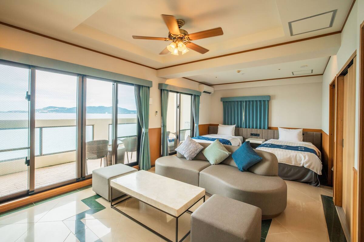 Een moderne hotelkamer met balkon, bed, een bank en een tafel.