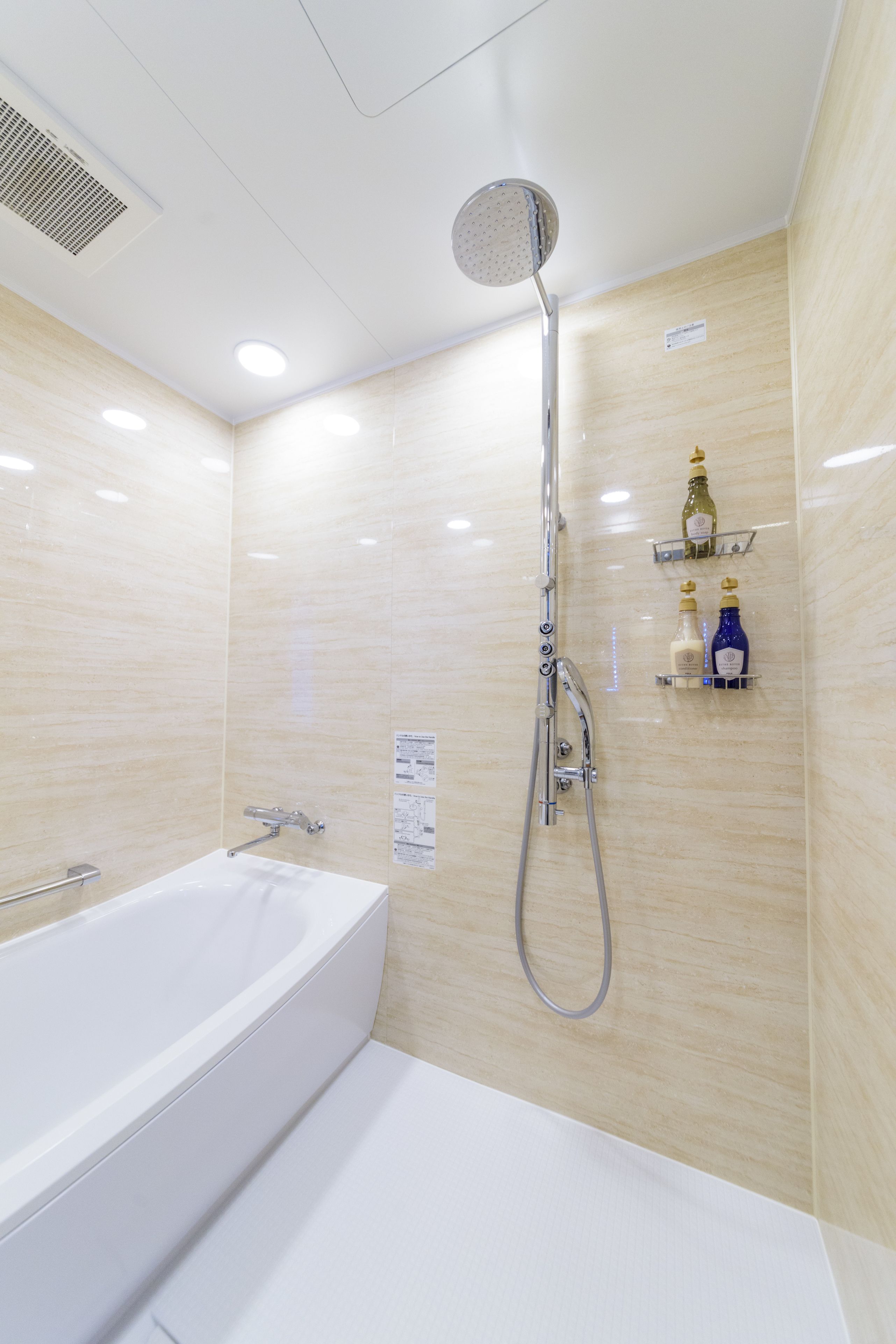 A modern bathroom with a bathtub, a showerhead, and a shelf with toiletries.