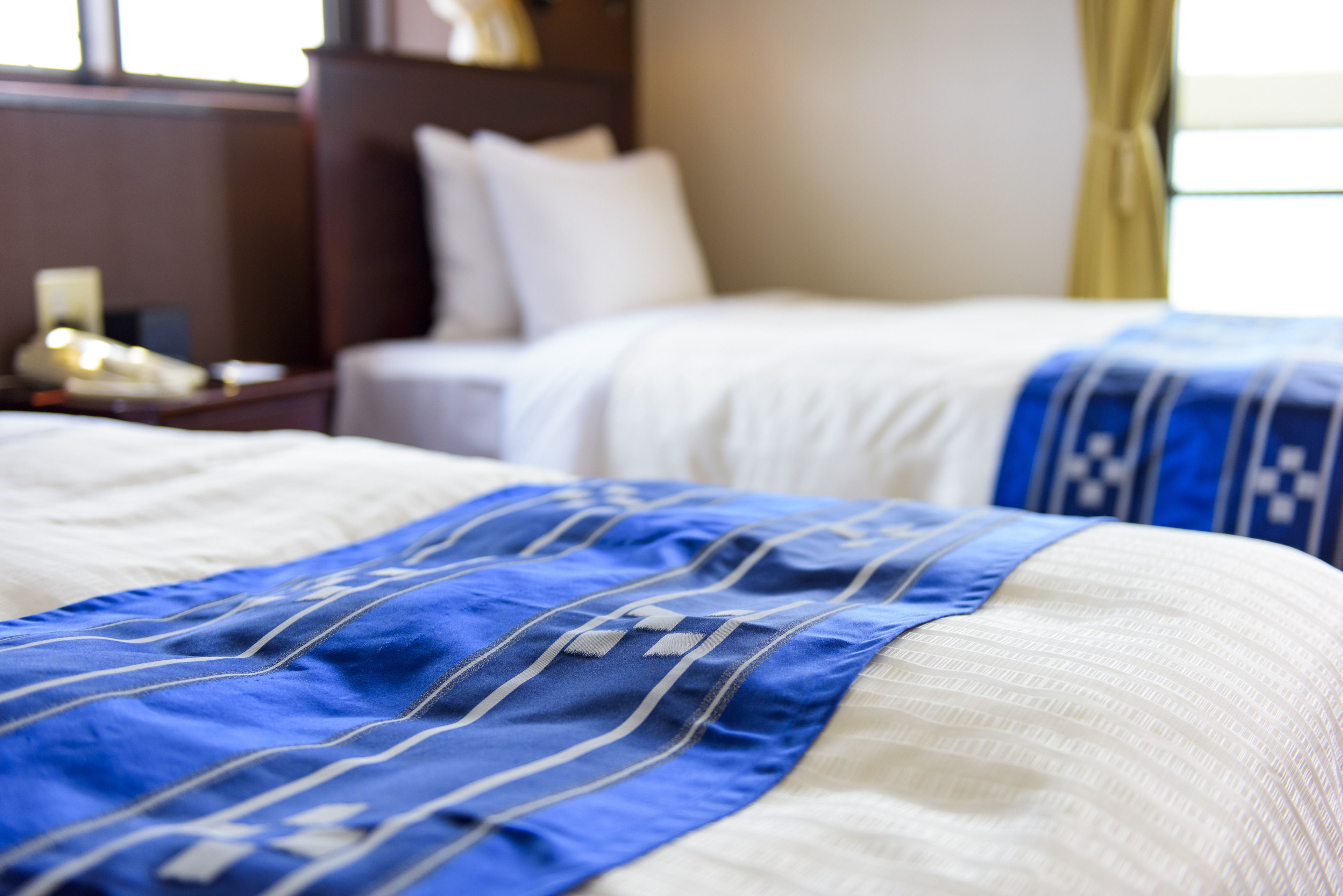 A hotel room with two beds, a nightstand, and a lamp.