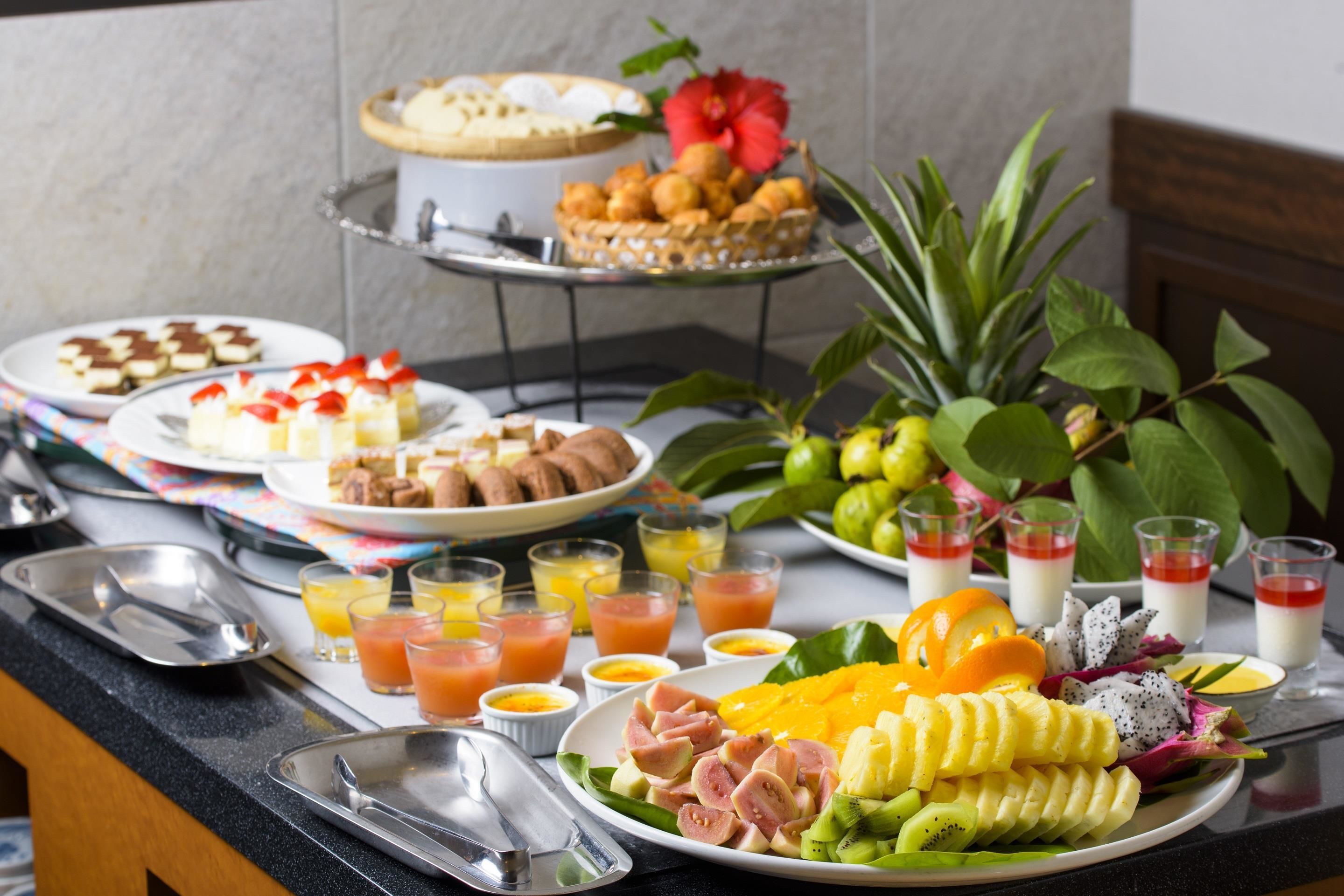 A breakfast buffet with various dishes, fruits, and beverages.