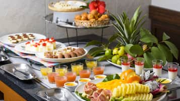 A breakfast buffet with various dishes, fruits, and beverages.