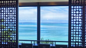 Uitzicht vanuit een kamer met een groot raam op een rustige zee.