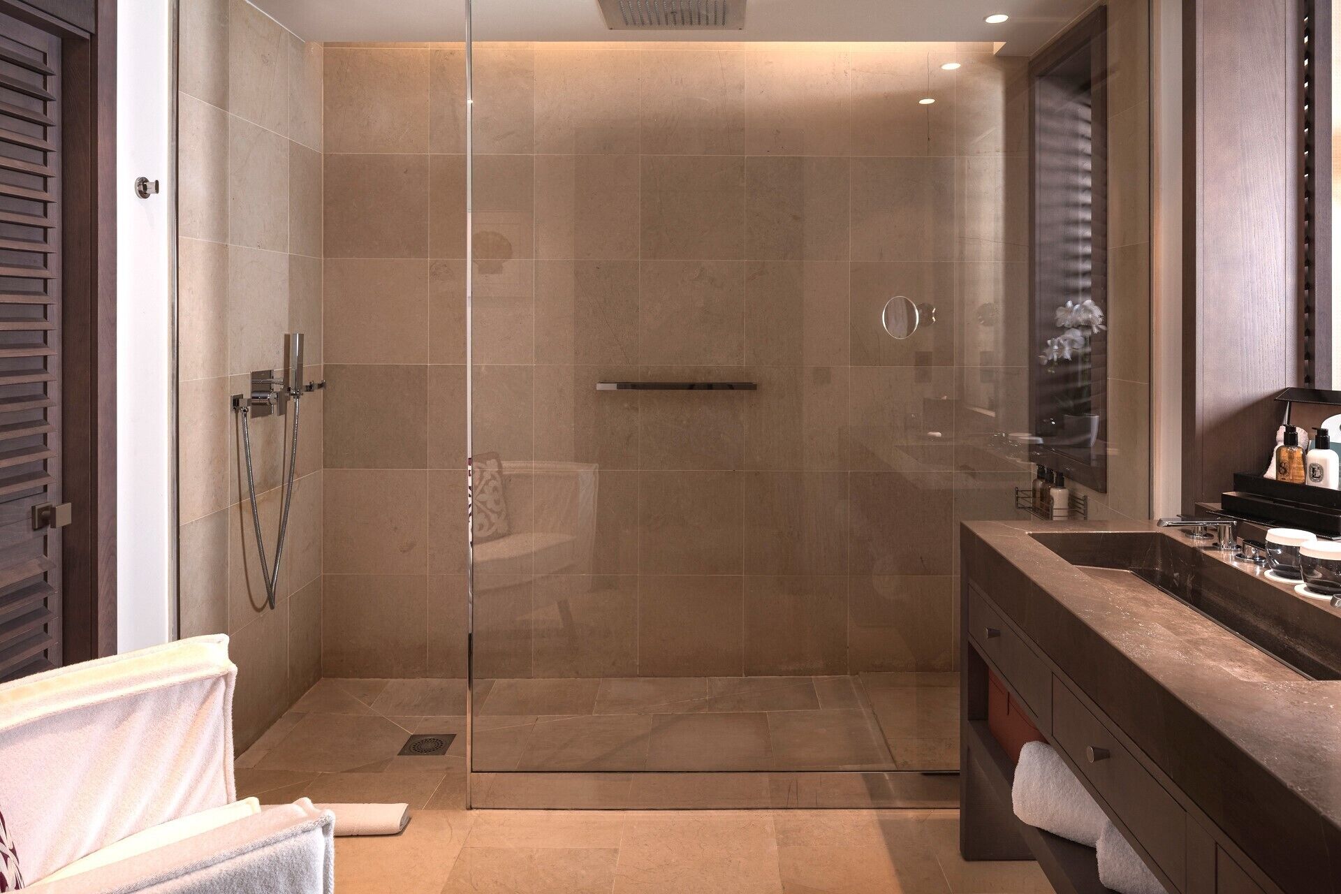 A modern bathroom with a glass-enclosed shower, a vanity with a sink, and a mirror.
