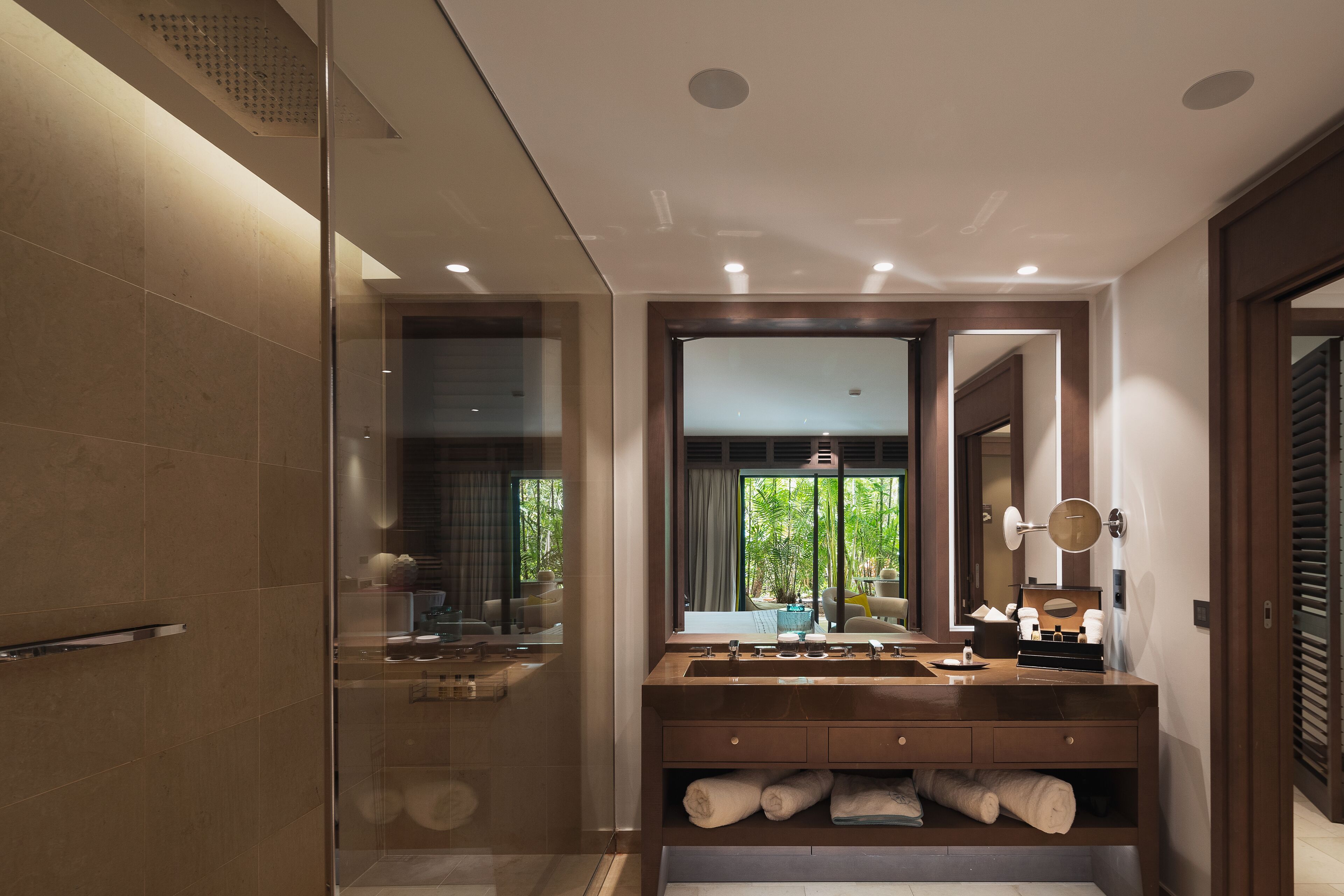 Un baño moderno con cabina de ducha de vidrio, un espejo grande y un tocador con toallas.