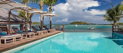 Alberca al aire libre, sombrillas en la alberca y camastros