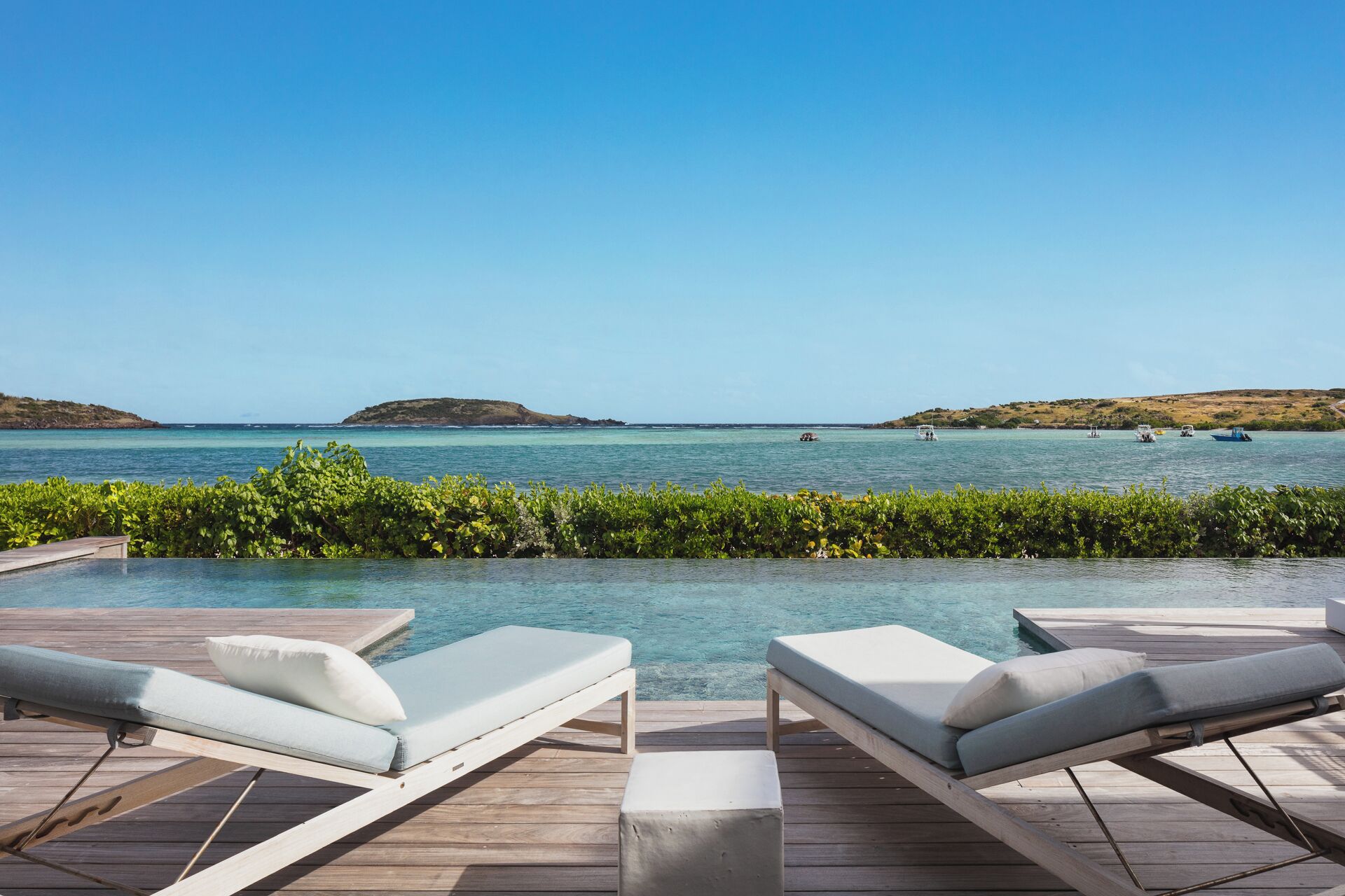 A poolside area with lounge chairs and a view of the sea.