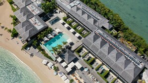 An aerial view of a resort with a swimming pool, beach, and multiple buildings with a uniform roof design. - Le Barthélemy Hotel & Spa (St. Barthelemy)