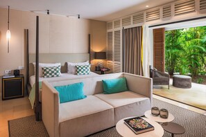 Habitación de hotel con una cama, un sofá, una mesita y vistas a un jardín exuberante.