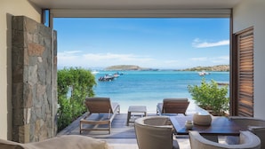 A patio with a view of the sea, stone walls, and outdoor furniture. - Le Barthélemy Hotel & Spa (St. Barthelemy)