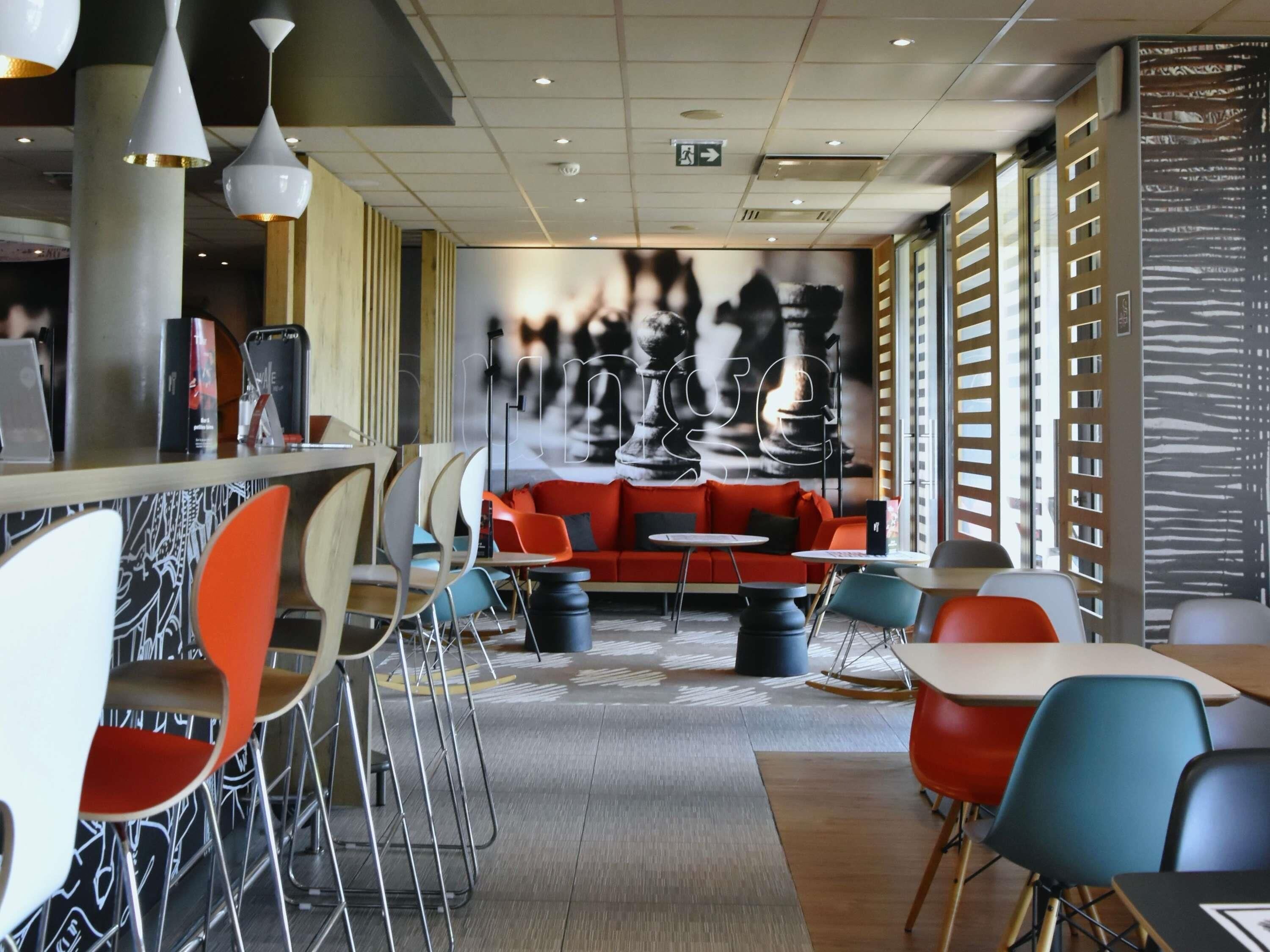 A modern interior with a bar area, seating arrangements, and a large abstract mural.