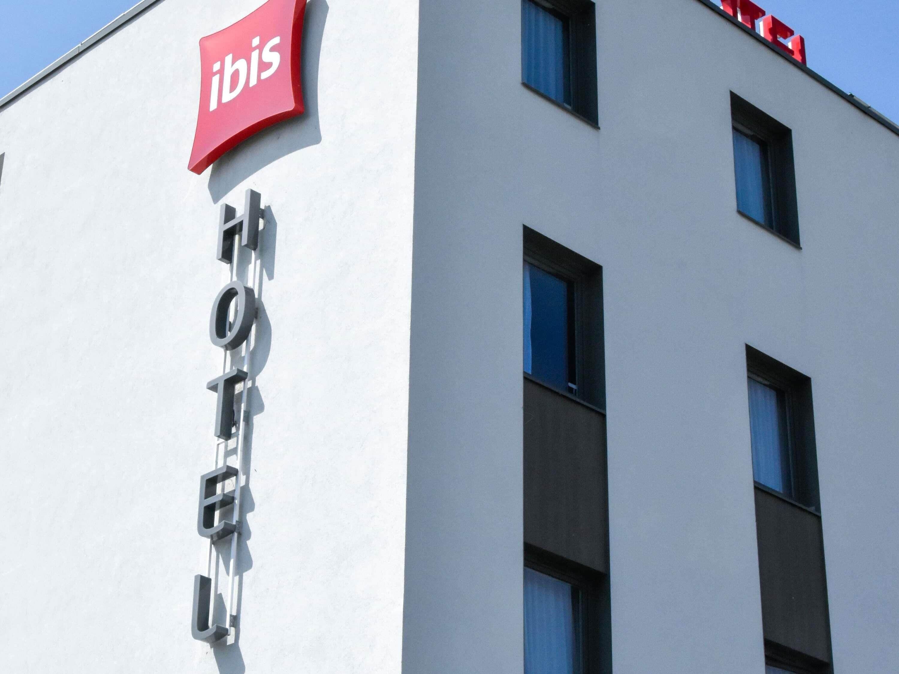 Un edificio con el letrero rojo de 'ibis' y la palabra 'HOTEL' en su fachada.