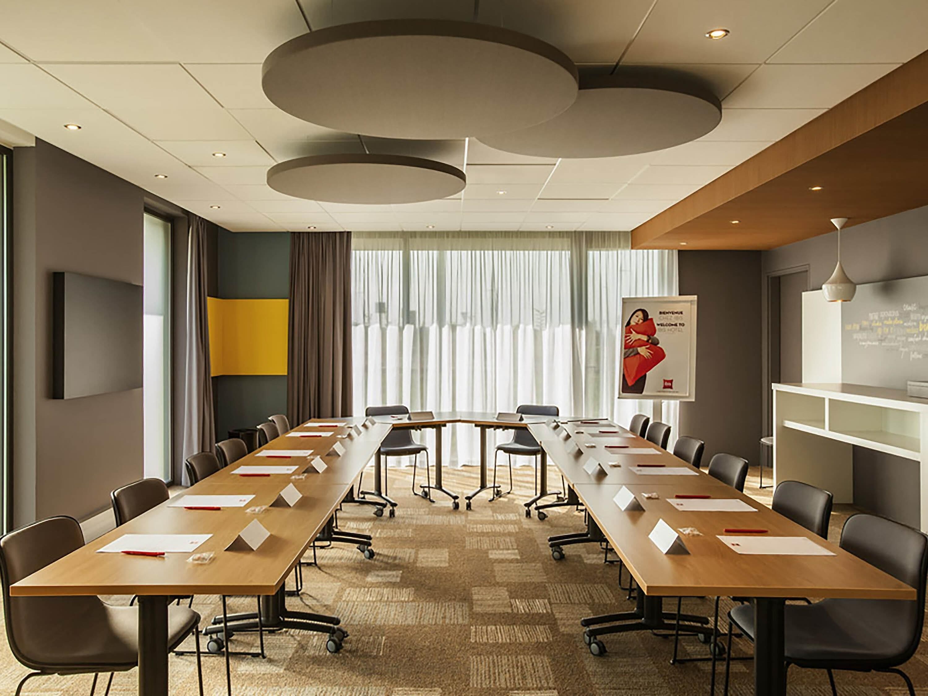 A conference room with a long table, chairs, a whiteboard, and a poster on the wall.