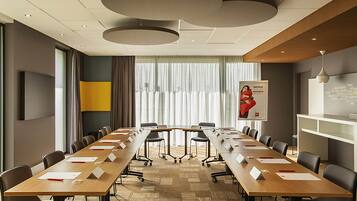 A conference room with a long table, chairs, a whiteboard, and a poster on the wall.