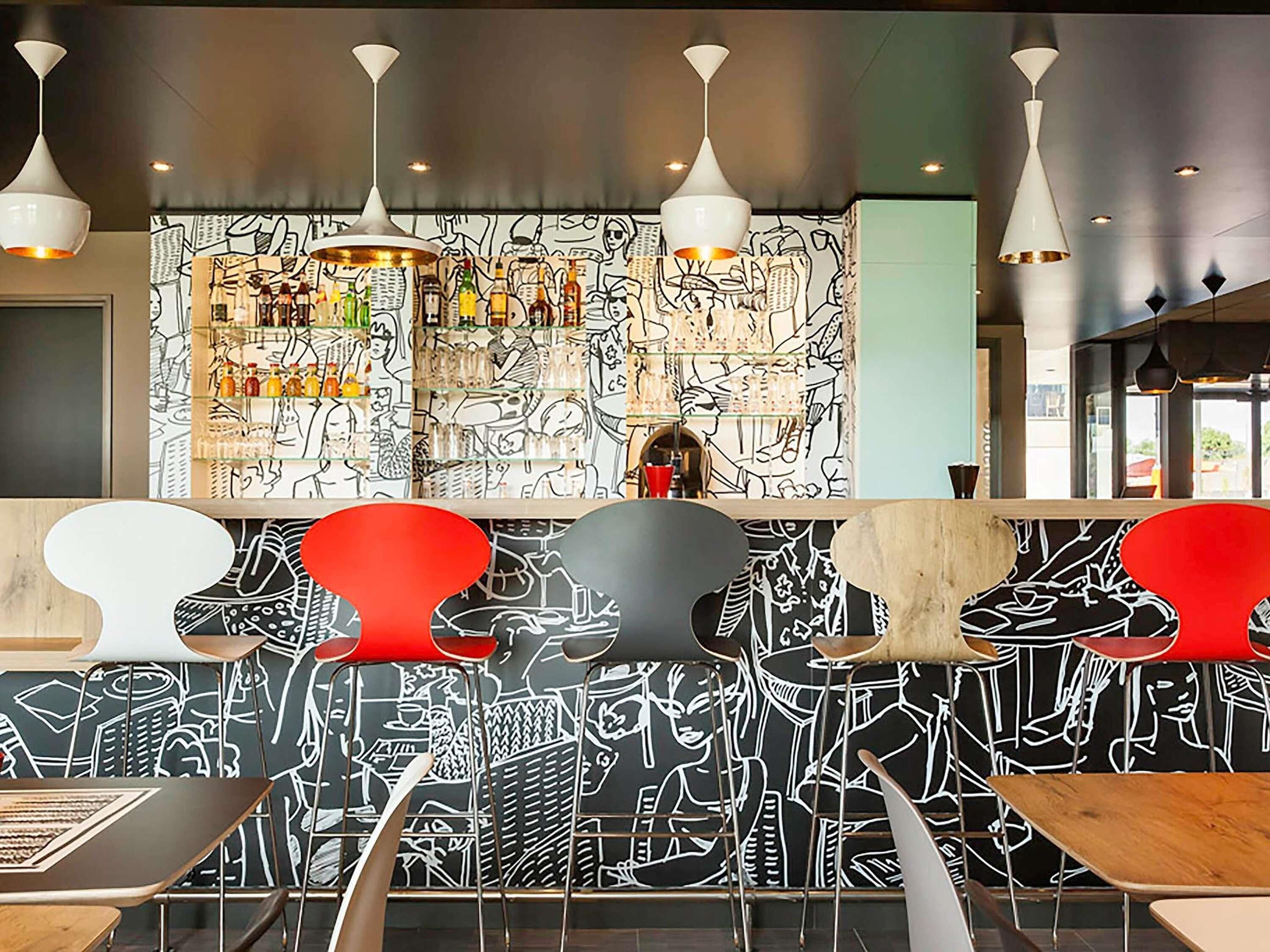 Una zona de bar con un mural, taburetes e iluminación colgante.