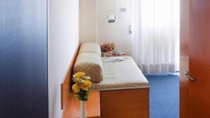Een slaapkamer met een bed, een nachtkastje, een vaas met bloemen en een deur.