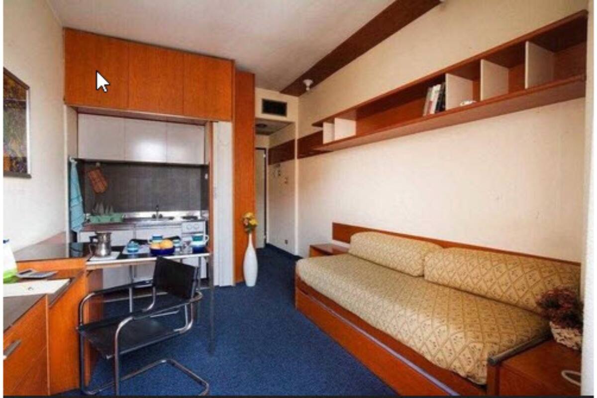 Una habitación compacta con kitchenette, cama y escritorio con silla.