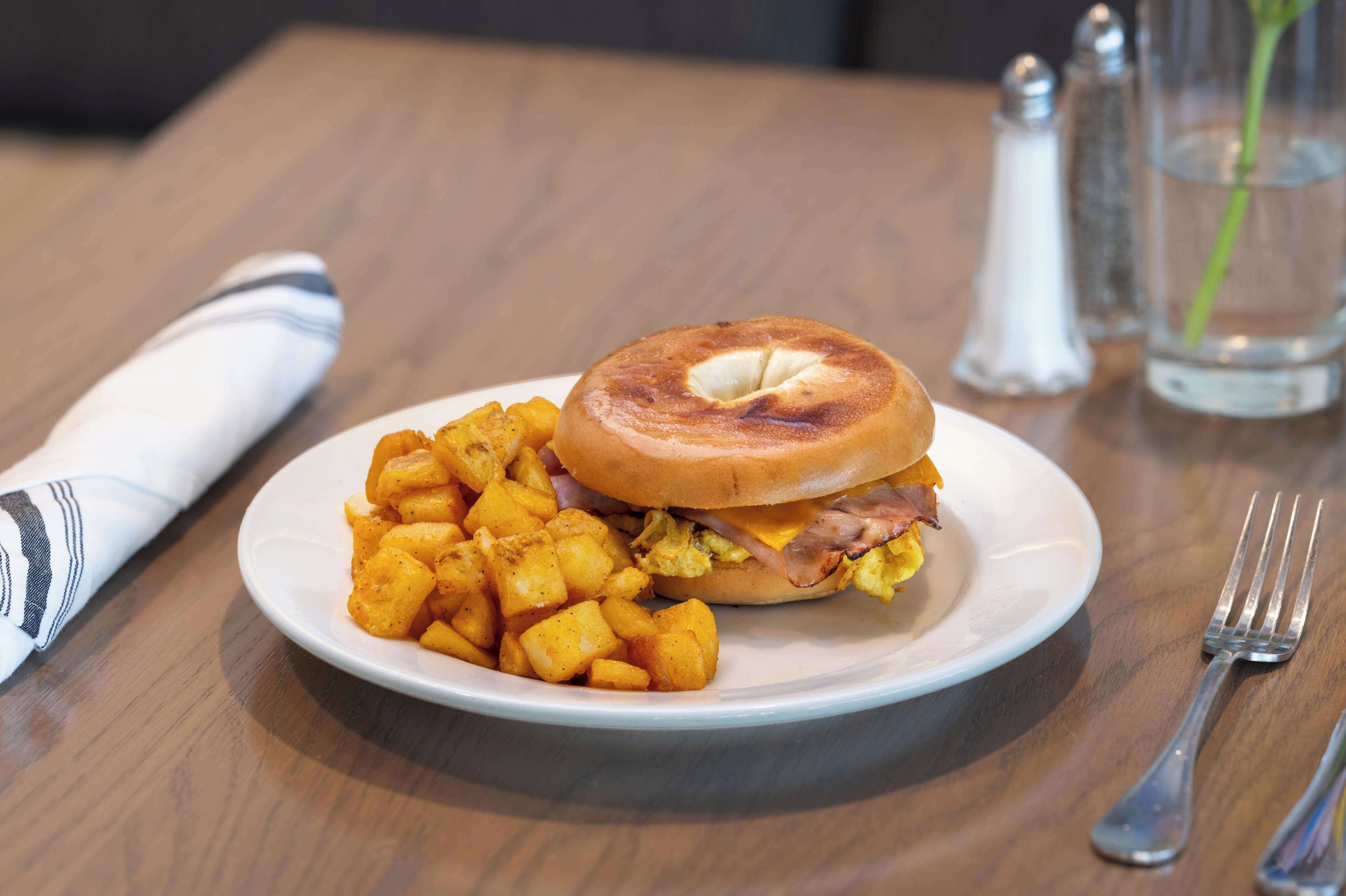 Une assiette avec un sandwich et des frites, posée sur une table en bois.