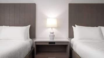 Une chambre d’hôtel avec deux lits, une table de chevet avec une lampe et un panneau de commande.