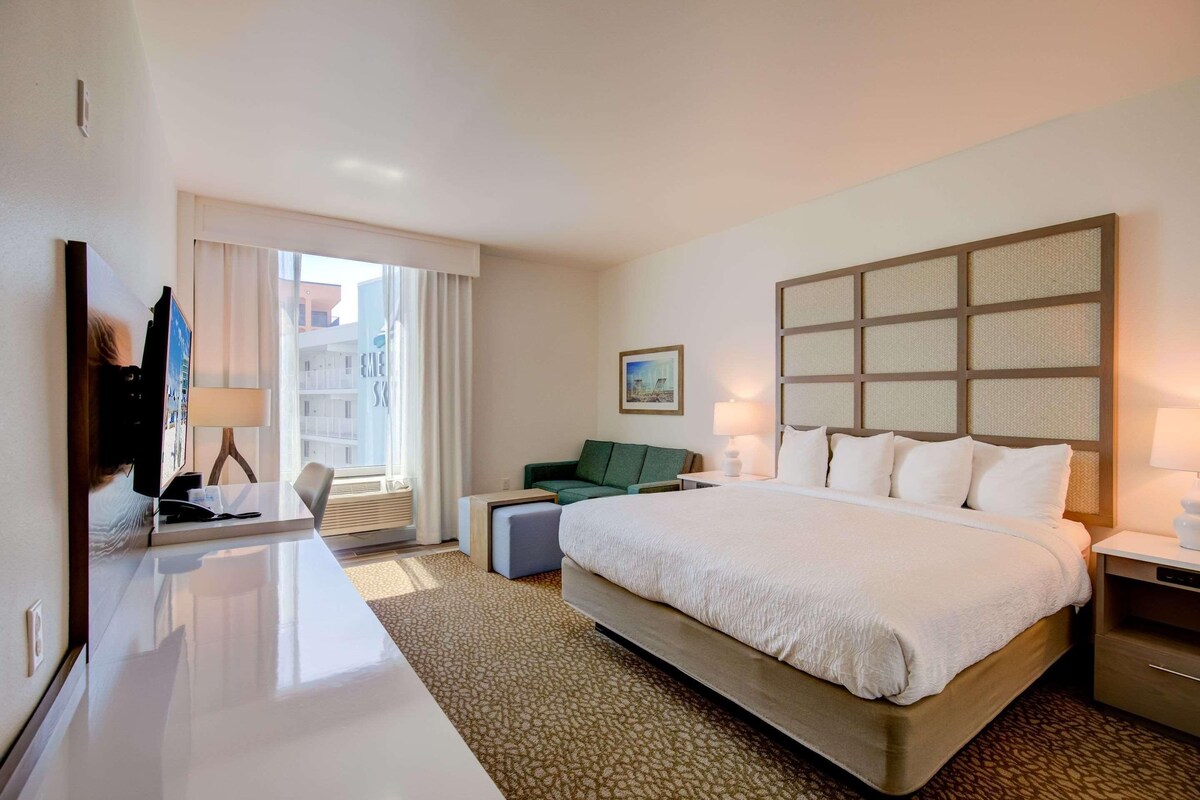 Una habitación de hotel con una cama grande, un escritorio, una silla, un sofá y un televisor.