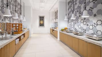 A modern kitchen with hexagonal tile walls, pendant lighting, and a central island with a wooden base.