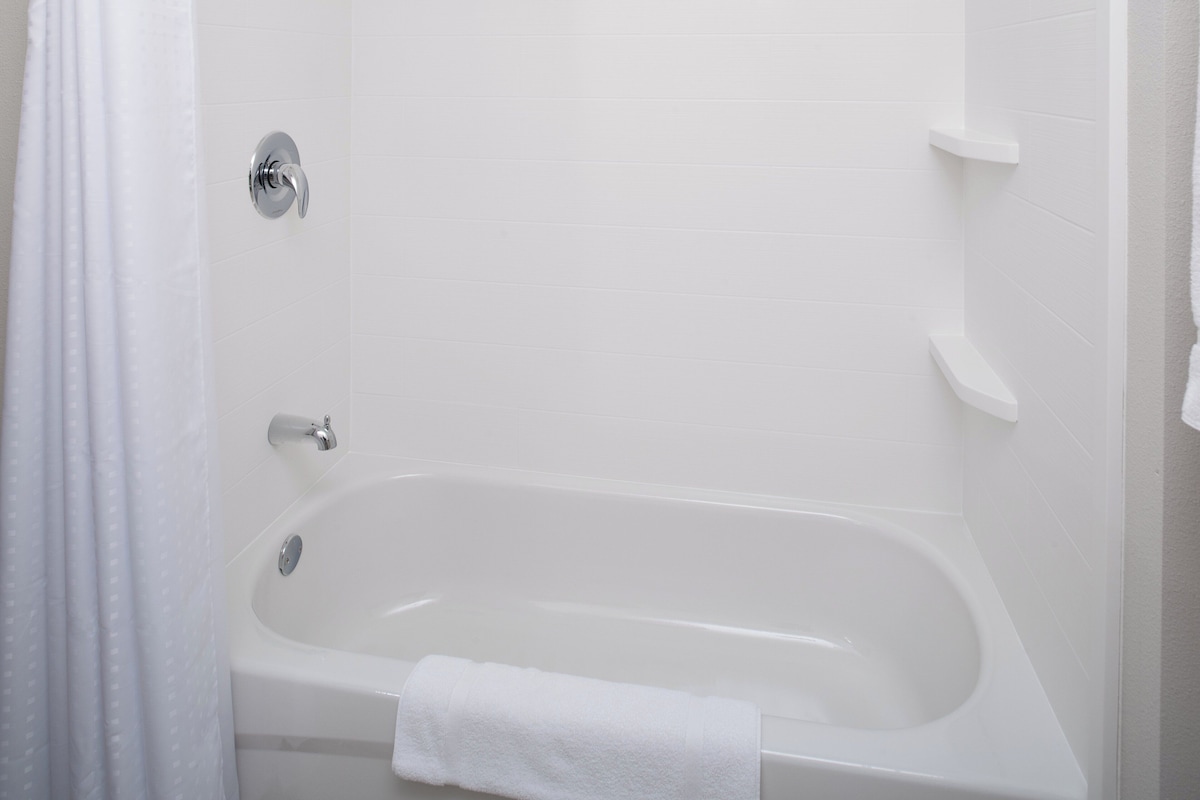 A white bathtub with a towel, a shower curtain, and a chrome faucet.